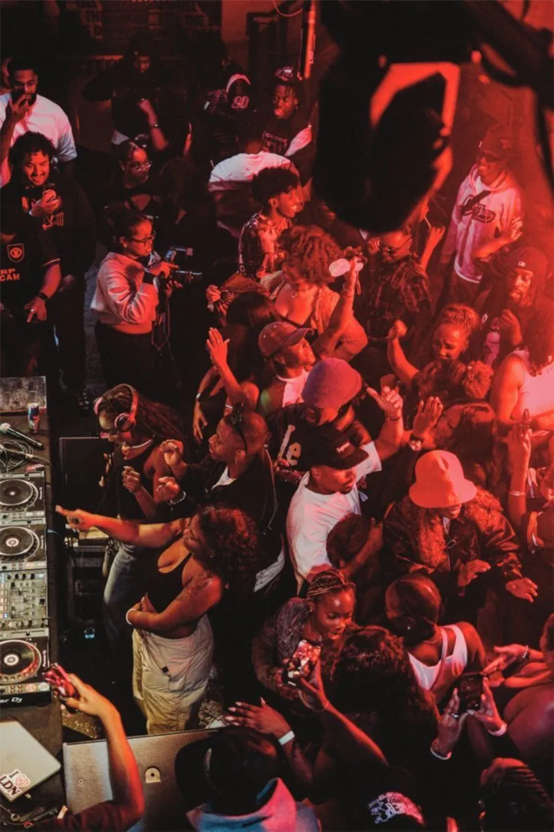 Danseurs réunis autour d'une platine DJ sous une lumière rouge, vue en plongée, Merzouk Lamara, Pessoa Connect.