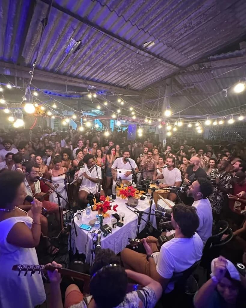 Roda de samba avec musiciens et public sous guirlandes lumineuses - ambiance soirée brésilienne